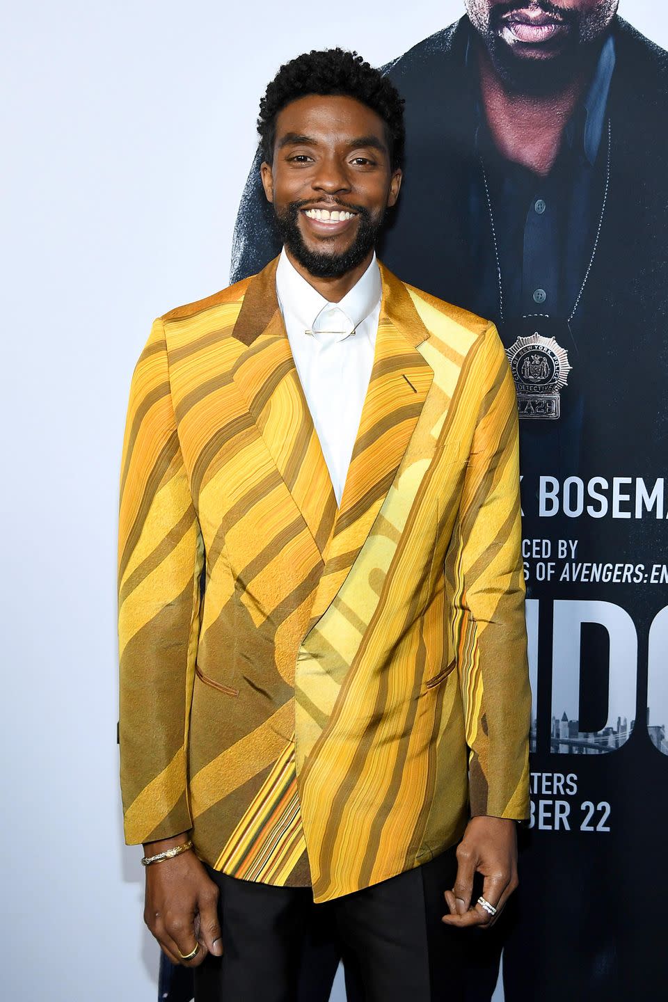 chadwick boseman, smiling in a yellow suit jacket in november 2019