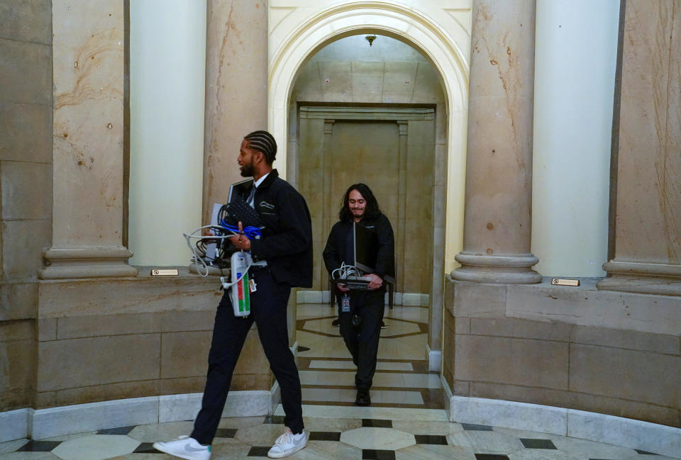 Two workers carry computer equipment.