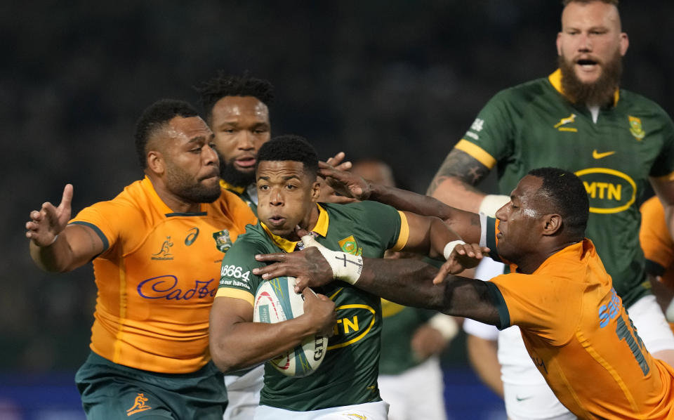 South Africa's Grant Williams, center, avoids a tackle by Australia's Suliasi Vunivalu, front right, during the Rugby Championship test match between South Africa and Australia at Loftus Versfeld stadium in Pretoria, South Africa, Saturday, July 8, 2023. (AP Photo/Themba Hadebe)
