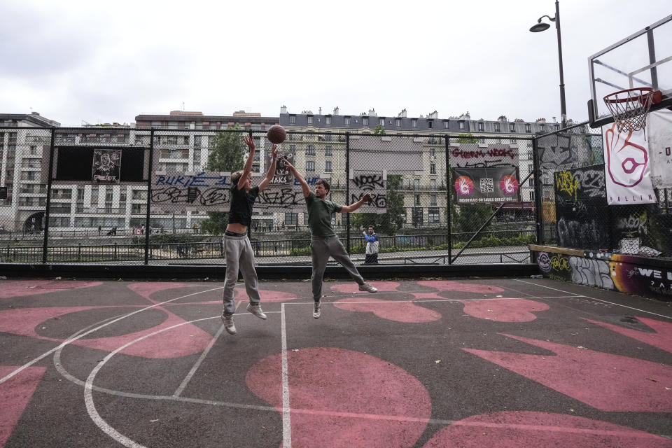 Youths play basketball at a court along the canal Saint Martin in Paris Sunday, June 16, 2024. New names will soon adorn replica NBA jerseys of French youths competing on basketball courts around Paris. Frenchmen Zaccharie Risacher, Alexandre Sarr and Tidjane Salaün are among the top picks in the NBA draft, where a second straight French No. 1 pick is expected after Victor Wembanyama last year. (AP Photo/Michel Euler)