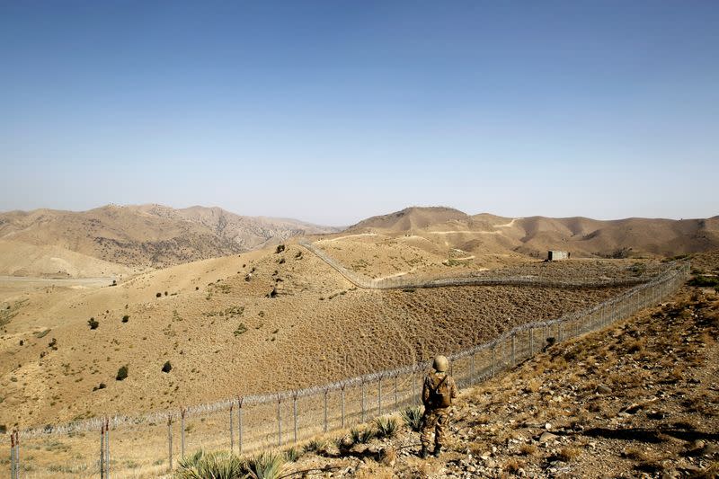 FILE PHOTO: A soldier stands guard along the border fence outside the Kitton outpost on the border with Afghanistan in North Waziristan