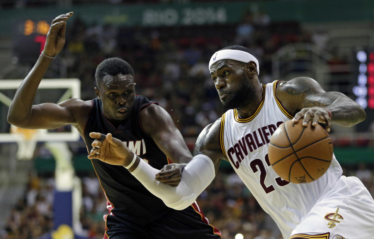 LeBron James, de los Cavaliers, (der) trata de burlar la marca de Luol Deng, del Miami Heat, durante un partido de pretemporada en Río de Janeiro el 11 de octubre del 2014. La vuelta de James a Cleveland puede hacer que los Cavaliers peleen finalmente el título. (AP Photo/Felipe Dana, File)