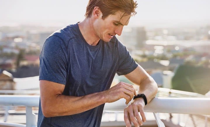 A man adjusts the settings on his Fitbit Charge 4 smartwatch.