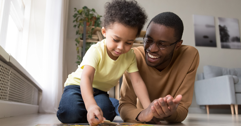 father and son doing a puzzle on the floor at home