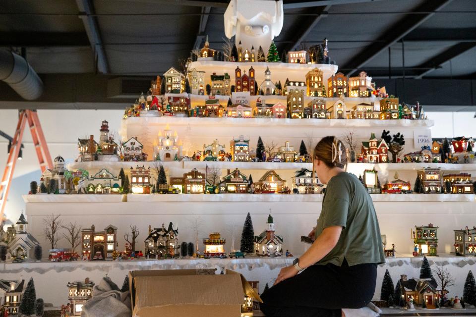 Allison Sights, an archivist at Graceland, sits up on the display of Enesco Christmas villages from over the years as she arranges trees and figurines as the Enesco Gift Shop & Gallery Featuring Department 56 exhibit is put together before its opening Thursday at Graceland Crossing in Memphis, Tenn., on Wednesday, Nov. 15, 2023.