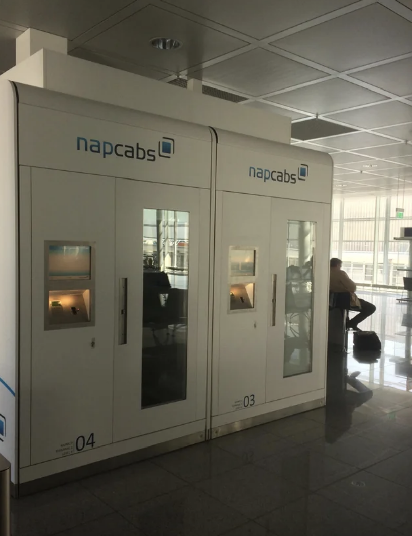 Private sleeping pods, labeled "napcabs," in an airport lounge