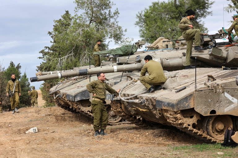 Soldados israelíes realizan mantenimiento a tanques desplegados en la frontera sur con la Franja de Gaza el 28 de noviembre de 2023