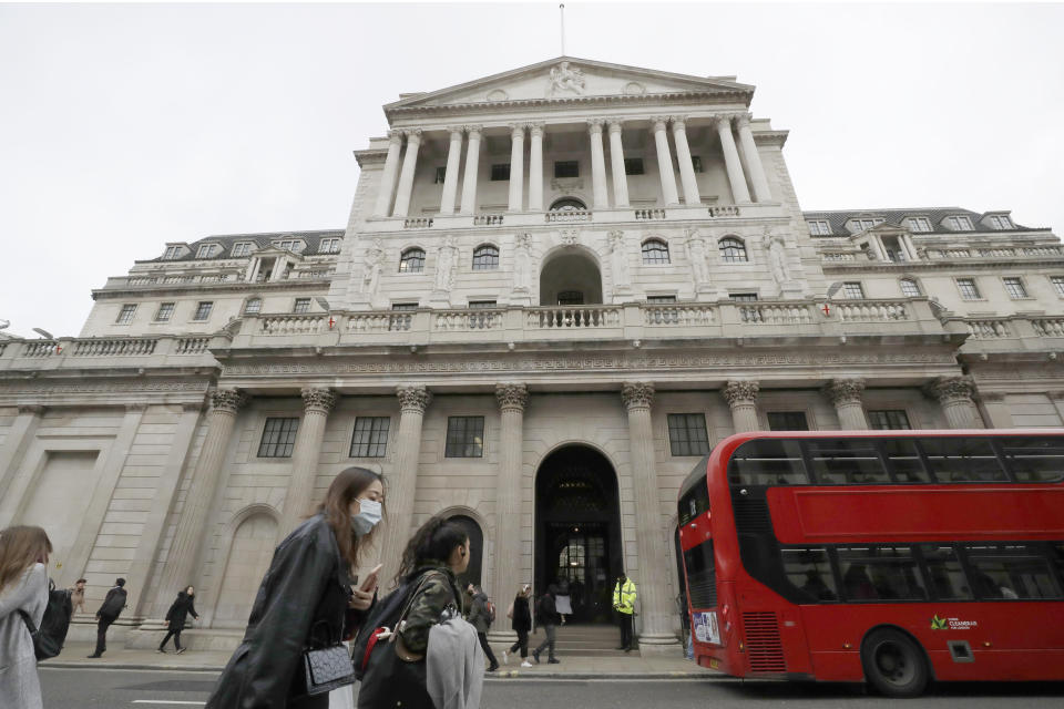 FILE - In this Wednesday, March 11, 2020 file photo, pedestrians wearing face masks pass the Bank of England in London.  The U.K. economy has officially fallen into a recession after official figures showed it contracting by a record 20.4% in the second quarter as a result of lockdown measures put in place to counter the coronavirus pandemic. The slump recorded by the Office for National Statistics follows a 2.2% quarterly contraction in the first three months of the year. ( (AP Photo/Matt Dunham, File)