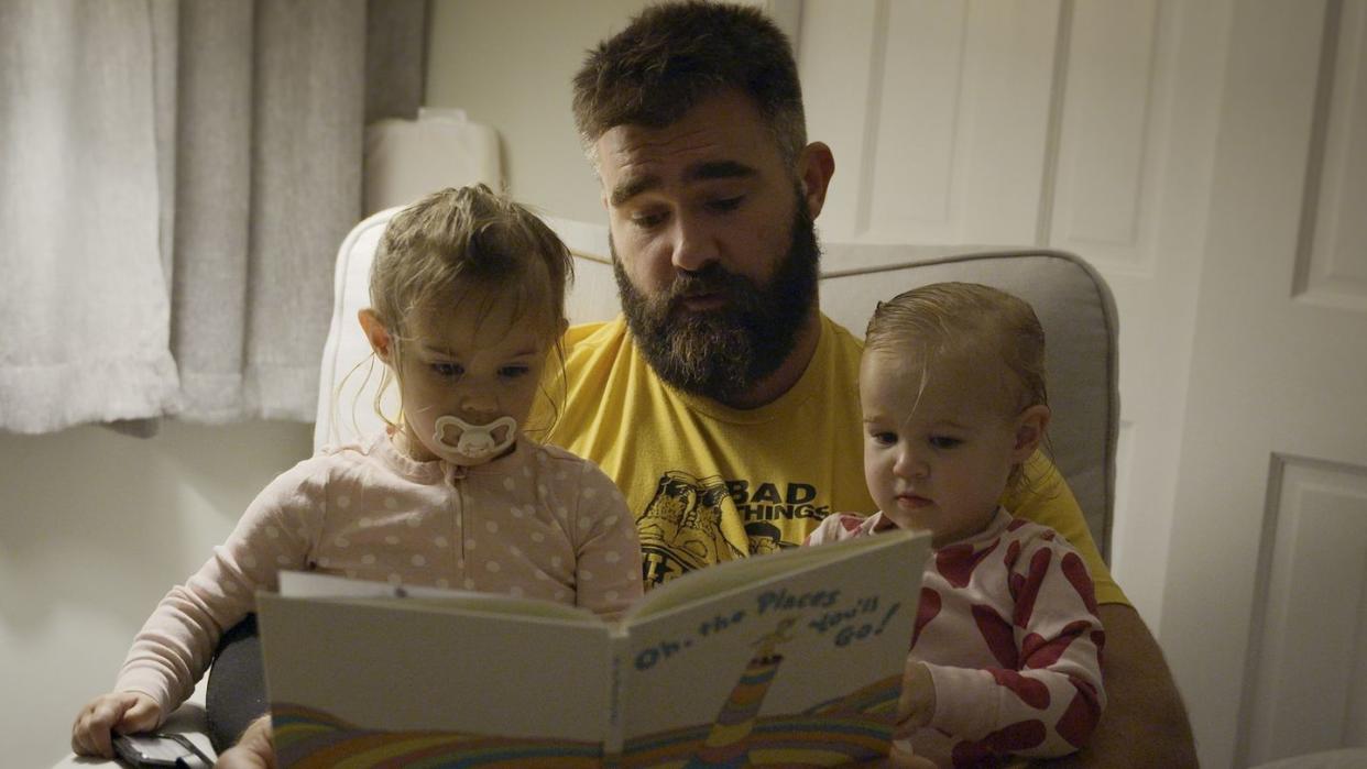 a person reading a book to two children