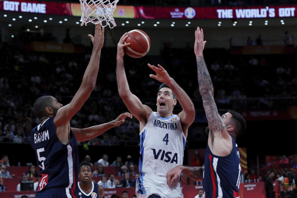 El argentino Luis Scola (4) intenta un enceste en medio de los franceses Nicholas Batum, izquierda, y Vincent Poirier durante el duelo en las semifinales de la Copa del Mundo de la FIBA, en la Arena Cadillac de Beijing, el viernes 13 de septiembre de 2019. (AP Foto/Andy Wong)