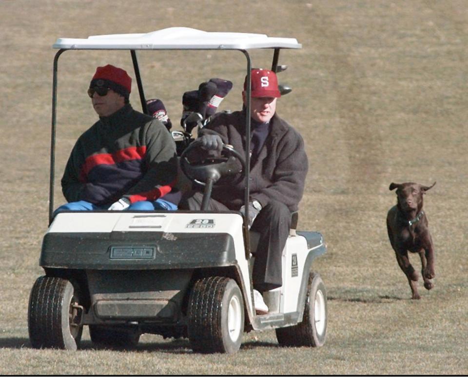 US President Bill Clinton (R) rides his golf cart down the 9th fairway with Tony Rodham, the brother of Hillary , as the Presidents dog Buddy chases behind during a round at the Maple Run Golf Club in Thurmont, Maryland. The President is spending the weekend at Camp David with his daughter Chelsea while his wife is traveling.