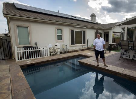 Home owner Steven Lista stands in his back yard under the solar panels he financed using a government sponsored system in Eastvale, California September 4, 2015. REUTERS/Mike Blake