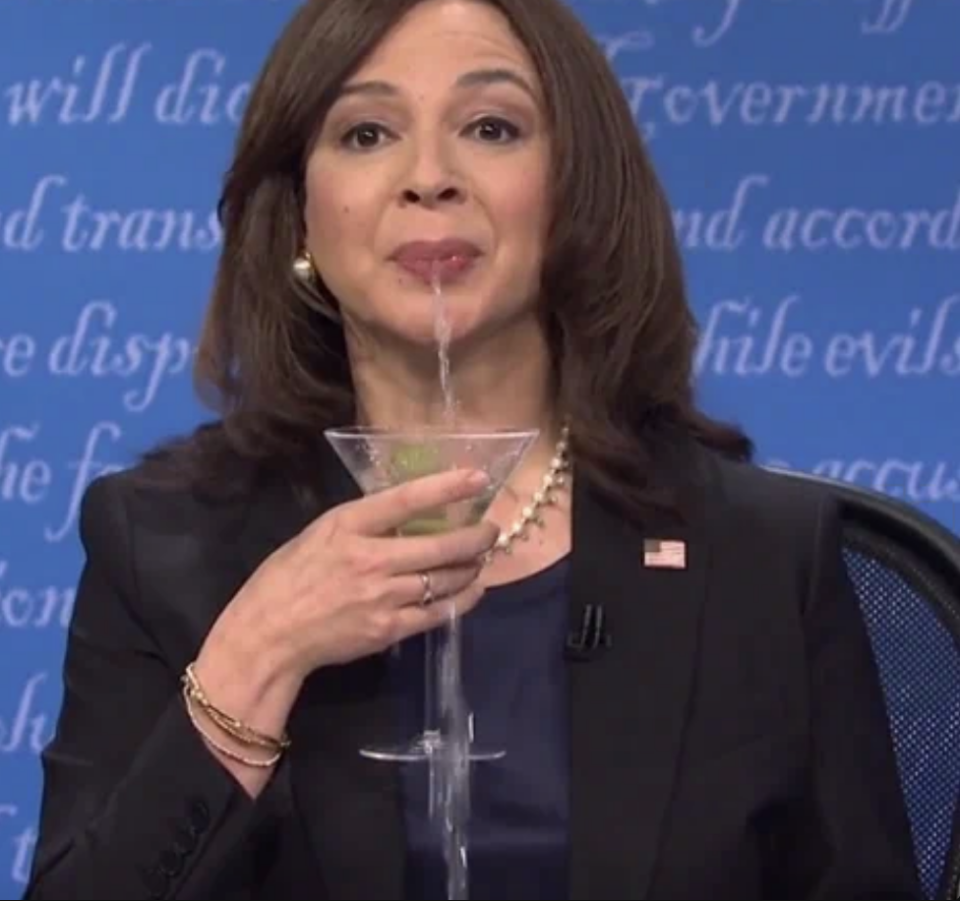 Maya Rudolph, dressed as Kamala Harris, humorously spits out her drink during a performance