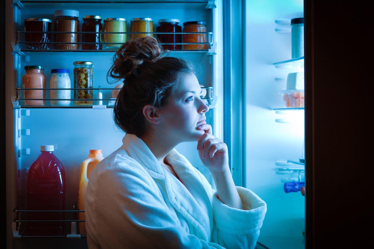 woman looking at fridge for something to eat, at night