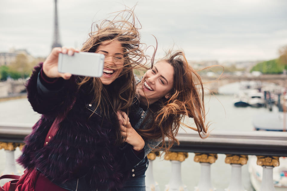 Young women in Paris taking selfie against the Seine river