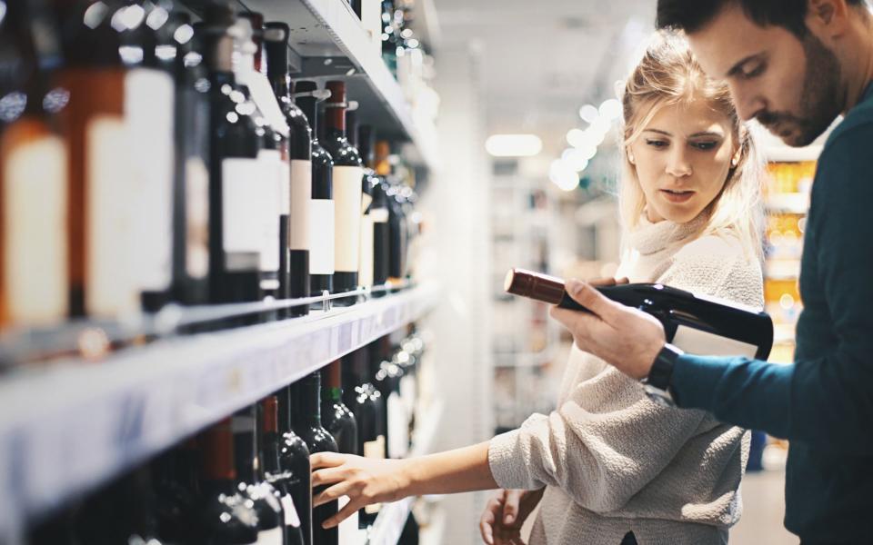 Couple choosing some red wine at local supermarket