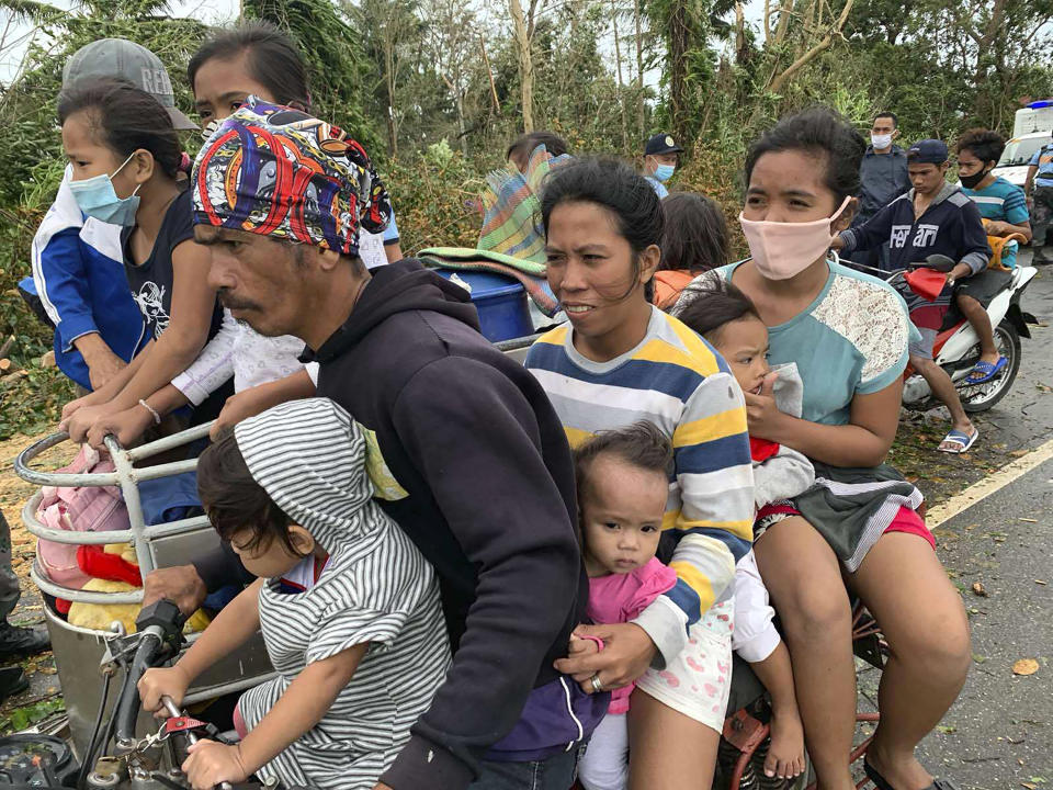 Residents evacuate to safer grounds in Pola town on the island of Mindoro, central Philippines, Monday, Oct. 26, 2020. A fast-moving typhoon forced thousands of villagers to flee to safety in provinces south of the Philippine capital Monday, flooding rural villages and ripping off roofs, officials said. (AP Photo/Erik De Castro)