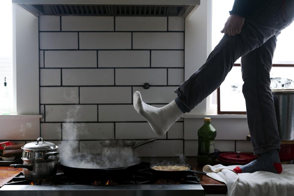 Jorge Sanhueza-Lyon stands on his kitchen counter to warm his feet over his gas stove during a snow storm on Feb. 16, 2021, in Austin.(AP Photo/Ashley Landis, File)