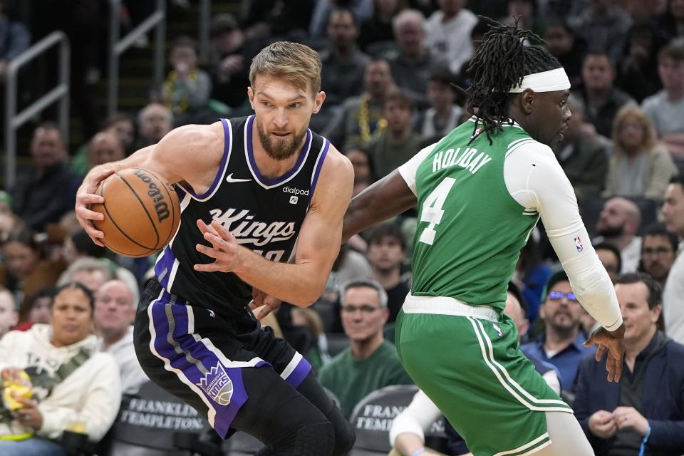 Sacramento Kings' Domantas Sabonis (10) turns away from Boston Celtics' Jrue Holiday (4) during the first half of an NBA basketball game Friday, April 5, 2024, in Boston. (AP Photo/Michael Dwyer)