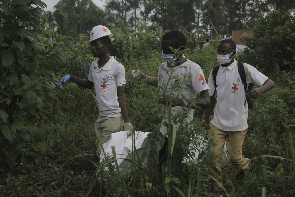 Red Cross volunteers carry the body of a civilian, who was killed in the Democratic Republic of Congo North Kivu province village of Mukondi, Thursday March 9, 2023. At least 36 were killed when the Allied Democratic Forces, a group with links to the Islamic State group, attacked the village and burned residents' huts. (AP Photo/Socrate Mumbere)