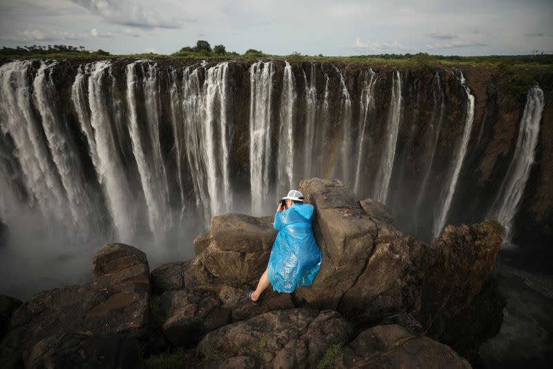 Visitors take pictures before dry cliffs following a prolonged drought at Victoria Falls