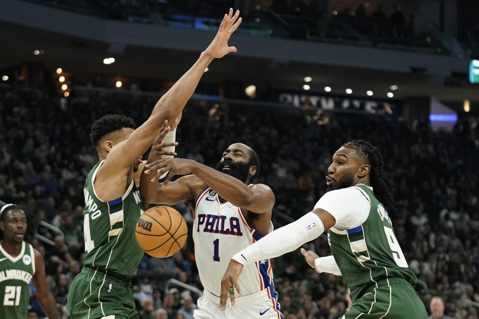 Philadelphia 76ers' James Harden (1) loses control of the ball as he drives between Milwaukee Bucks' Giannis Antetokounmpo, front left, and Jae Crowder, right, during the first half of an NBA basketball game Saturday, March 4, 2023, in Milwaukee. (AP Photo/Aaron Gash)