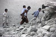 Survivors of an earthquake walk on rubble of a mud house after it collapsed following the quake in the town of Awaran, southwestern Pakistani province of Baluchistan, September 25, 2013. The death toll from a powerful earthquake in Pakistan rose to at least 208 on Wednesday after hundreds of mud houses collapsed on people in a remote area near the Iranian border, officials said. (REUTERS/Sallah Jan)