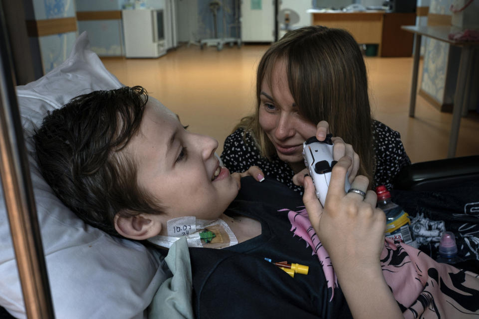 Yuliia Vasylenko smiles with her son Denys, 11, as he plays on a video game console at the National Cancer Institute in Kyiv, Ukraine, Wednesday, July 10, 2024. Denys is one of 31 young patients battling cancer who were relocated to the hospital from Okhmatdyt Children’s Hospital after it was struck by a Russian missile this week. (AP Photo/Alex Babenko)