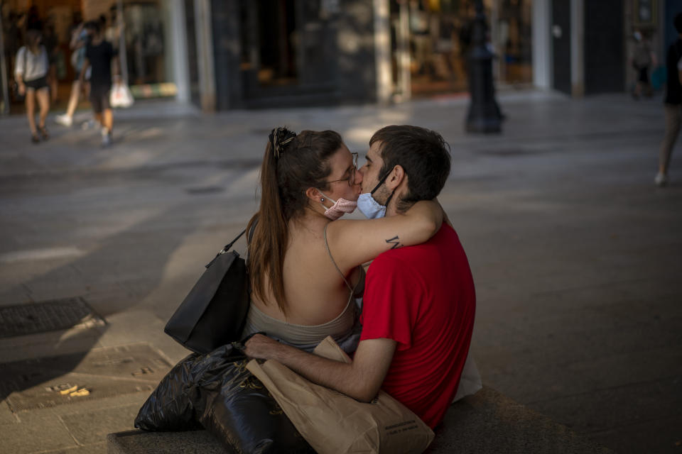 A couple wearing face masks to prevent the spread of coronavirus kiss in downtown Barcelona, Spain, Tuesday, Sept. 15, 2020. Spain's official death toll for the new coronavirus on Tuesday surpassed 30,000 fatalities as the country's caseload also increased beyond 600,000, becoming the first European country to overcome that threshold. (AP Photo/Emilio Morenatti)