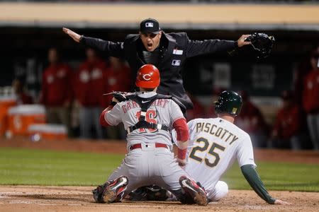 May 7, 2019; Oakland, CA, USA; Umpire Mark Ripperger (90) calls Oakland Athletics right fielder Stephen Piscotty (25) safe as Cincinnati Reds catcher Tucker Barnhart (16) looks for the call during the second inning at Oakland Coliseum. Mandatory Credit: Stan Szeto-USA TODAY Sports