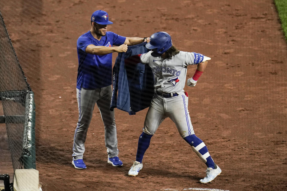 Toronto Blue Jays' Bo Bichette, right, is helped to put on a blazer by pitcher Jose Berrios after hitting a two-run home run off Baltimore Orioles starting pitcher Keegan Akin during the seventh inning of the second game of a baseball doubleheader, Saturday, Sept. 11, 2021, in Baltimore. (AP Photo/Julio Cortez)