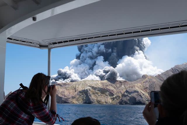 <p>(Xinhua/ via Getty Images</p> A person takes photos of volcanic eruption at New Zealand's White Island, Dec. 9, 2019.