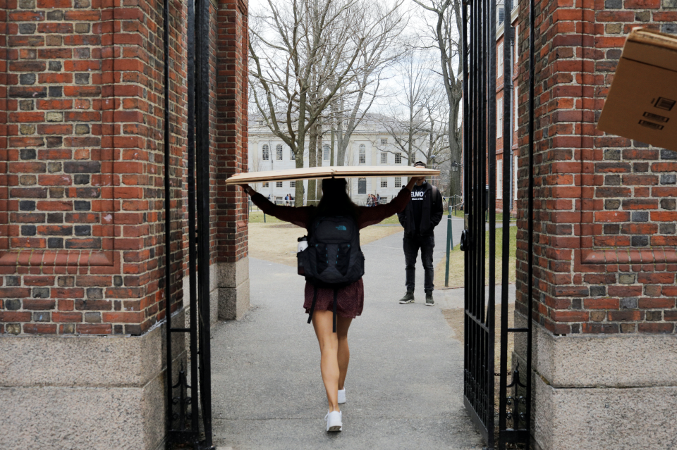 A student carries a box to her dorm at Harvard University after the school asked its students not to return to campus after Spring Break in Cambridge, Massachusetts, U.S., March 10, 2020. (Photo: REUTERS/Brian Snyder)