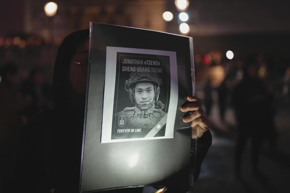 A woman holds a picture of Taiwanese volunteer who died in Ukraine at a vigil at the Trafalgar Square organised by the Ukrainian and US Embassy, ahead of the one-year anniversary of the invasion of Ukraine, in London, Thursday, Feb. 23, 2023. (AP Photo/Kin Cheung)