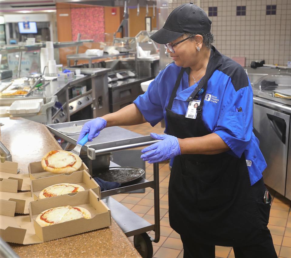Akron Children's Hospital Kids Cafe worker Tami Carter boxes up pizzas hot out of the oven. Hospitals are struggling to hire enough staff in food and environmental services, as well as nurses and other patient-care providers.