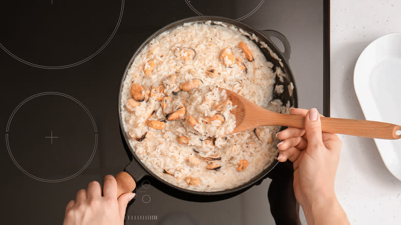 person cooking risotto in pan on stovetop 