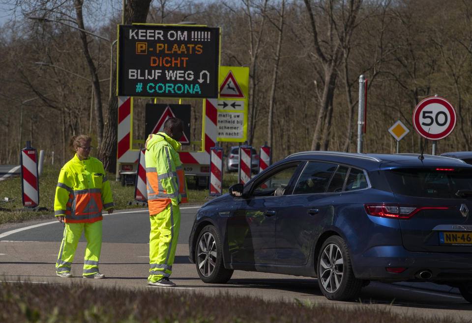 Regulators turn back non-essential traffic as a sign in Dutch reads "turn around, closed parking lot, stay away, #corona" on a road leading to the beach resort of Zandvoort, Netherlands, Saturday, April 4, 2020. The Dutch appeared to heed government directives to stay clear of forests, beaches and parks to avoid large crowds and the risk of spreading the coronavirus. (AP Photo/Peter Dejong)