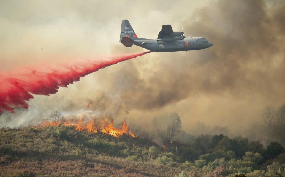 A U.S. Air Force plane drops fire retardant on a burning hillside in the Ranch Fire.