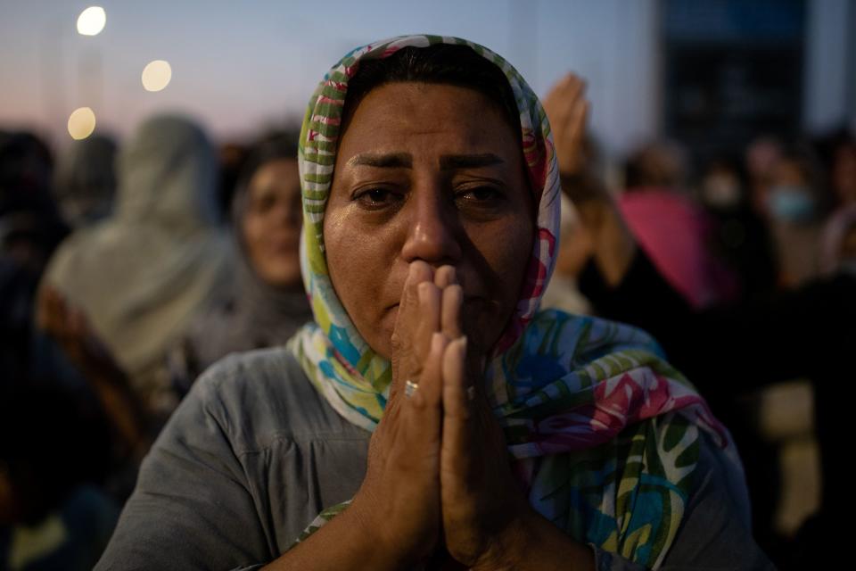 A woman reacts as refugees and migrants from the destroyed Moria camp pray near a new temporary camp where they will be accommodated, on the island of Lesbos, Greece, September 13, 2020. REUTERS/Alkis Konstantinidis