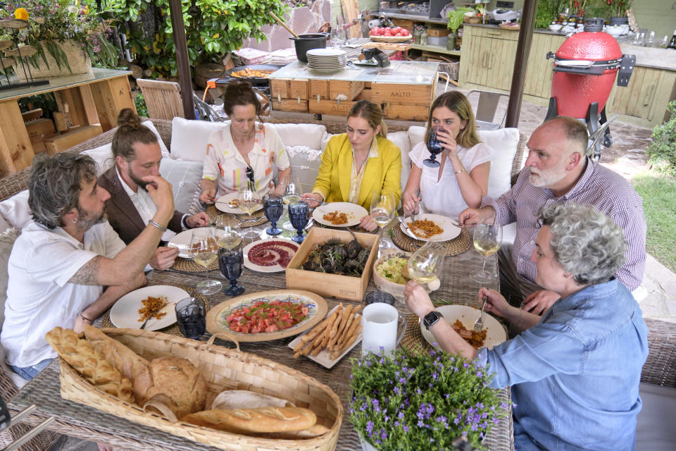 In this image provided by Discovery, Diego Guerrero, from left, Carlos Sanchez, Mila, Ines Andres, Carlota Andres, Jose Andres and Pepa Muñoz enjoy a meal the chefs prepared at Muñoz's house in a scene from the Discovery + television series "Jose Andres and Family in Spain." (Xaume Olleros/Discovery via AP)