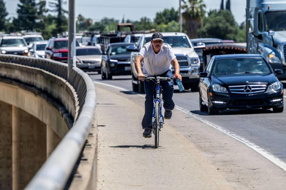 A bicyclist rides Monday with traffic on the Highway 70 bridge into downtown Marysville, towards the detour around the burnt-out Hotel Marysville in the center of the city. 