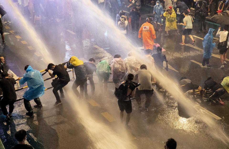 Pro democracy demonstrators face water canons as police try to disperse them from their protest venue in Bangkok, Thailand, Friday, Oct. 16, 2020. Thailand prime minister has rejected calls for his resignation as his government steps up efforts to stop student-led protesters from rallying in the capital for a second day in defiance of a strict state of emergency. (AP Photo/Gemunu Amarasinghe)