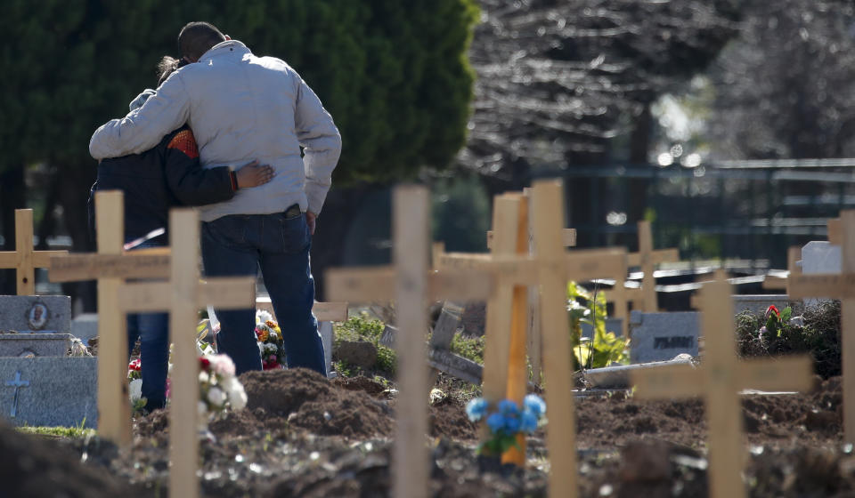 A couple embraces at a section of the Flores Cemetery where COVID-19 victims are being buried in Buenos Aires, Argentina, Monday, Aug. 10, 2020. Dr. Rodolfo Rossi from the city of La Plata says that “It’s not the same to die alone than with company, and it’s not the same to say goodbye than not to.” (AP Photo/Natacha Pisarenko)