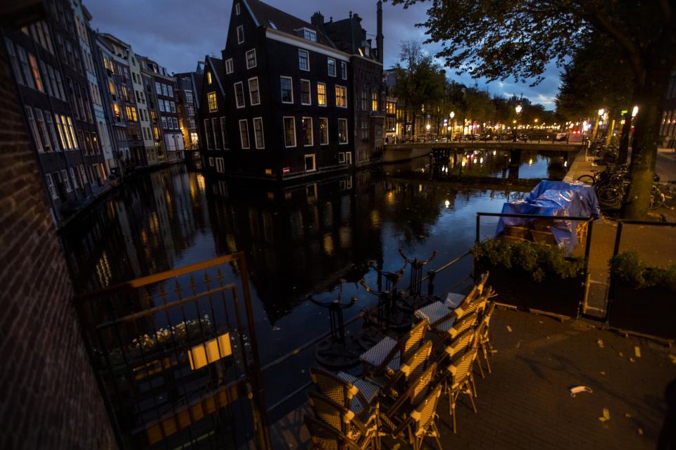 Terrace chairs are stacked outside a bar in the historic center of Amsterdam, Netherlands, Friday, Oct. 23, 2020. In much of Europe, city squares and streets, be they wide, elegant boulevards like in Paris or cobblestoned alleys in Rome, serve as animated evening extensions of drawing rooms and living rooms. As Coronavirus restrictions once again put limitations on how we live and socialize, AP photographers across Europe delivered a snapshot of how Friday evening, the gateway to the weekend, looks and feels. (AP Photo/Peter Dejong)