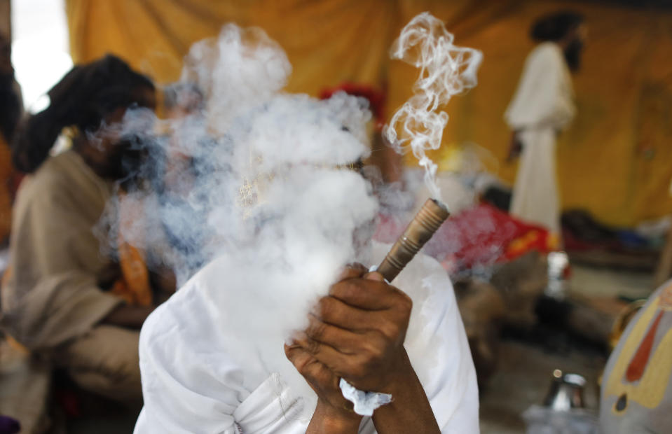 A Hindu holy, man smokes after a holy dip at Sangam during Magh Mela festival, in Prayagraj, India. Tuesday, Feb.16, 2021. Millions of people have joined a 45-day long Hindu bathing festival in this northern Indian city, where devotees take a holy dip at Sangam, the sacred confluence of the rivers Ganga, Yamuna and the mythical Saraswati. Here, they bathe on certain days considered to be auspicious in the belief that they be cleansed of all sins. (AP Photo/Rajesh Kumar Singh)