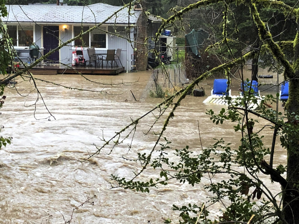 Homes are flooded by overflowing Issaquah Creek in Issaquah, Wash., as heavy rains pound the area Thursday, Feb. 6, 2020. Rain storms are triggering flood warnings on rivers across western Washington state. (AP Photo/Martha Bellisle)