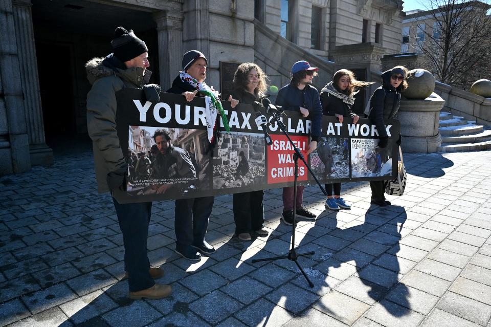 Local activists hold one of the signs that were recently removed from the outside of WRTA buses. From left, Scott Schaeffer-Duffy, Mohamad Alrifai, Roxanne Bruno, Evren Pallares, Rebecca Panwala and Claire Schaeffer-Duffy.