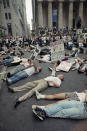 FILE - In this Thursday, Sept. 14, 1989 file photo, protestors lie on the street in front of the New York Stock Exchange in a demonstration against the high cost of the AIDS treatment drug AZT. The protest was organized by the gay rights activist group ACT UP. In response to protests, the FDA agreed to speed testing and approval of new therapies — a key step in curbing the high death toll from AIDS. Activist Larry Kramer, who died in May, said the protesters’ sense of rage made a difference. “Until you have anger and fear, you don’t have any kind of an activist movement,” he told Metro Weekly, a Washington-based LGBT publication, in 2011. (AP Photo/Tim Clary, File)