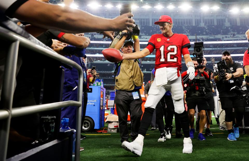 Buccaneers quarterback Tom Brady hands the ball off to a fan after the game against the Cowboys.