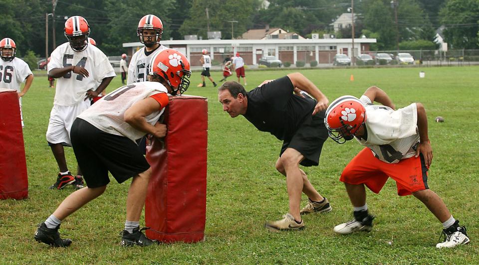Dover High School assistant football coach Rob Ambrosino, center, demonstrates blocking exercises during practice Thursday, Aug. 13, 2009.